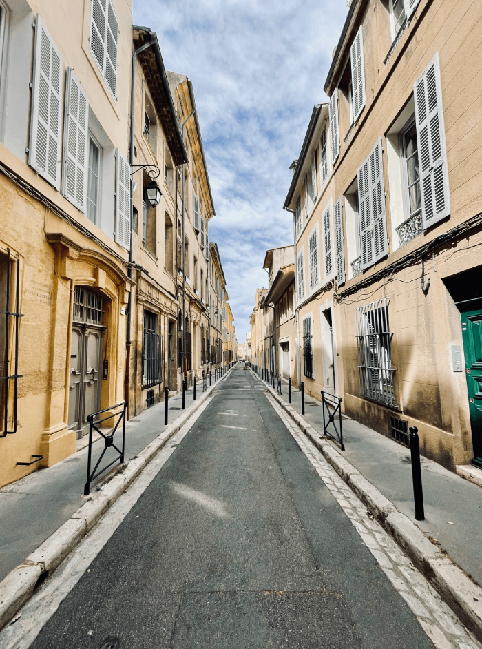 Cette photo capture la magie des rues pittoresques d'Aix-en-Provence, un véritable trésor au cœur de la Provence. Les rues pavées bordées d'élégantes façades ocre créent un décor digne d'une carte postale. À chaque coin de rue, on découvre des surprises architecturales et des petits trésors historiques. Se promener dans ces ruelles, c'est s'imprégner de l'atmosphère envoûtante de cette ville. Les fontaines murmurent des histoires anciennes, les terrasses de café invitent à la détente, et les boutiques artisanales exposent des trésors locaux. L'ombre des platanes offre un abri bienvenu lors des chaudes journées d'été, créant des espaces où l'on peut se rafraîchir et contempler la vie qui s'écoule. Aix-en-Provence est une destination qui envoûte les visiteurs avec son charme provençal intemporel. Chaque rue raconte une histoire, chaque coin dévoile un morceau de l'âme de la ville. Une visite ici est une véritable aventure au cœur de la Provence, un voyage à travers les sens et l'histoire.