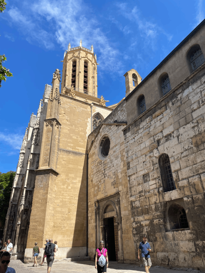 Cette image saisit la grandeur et la majesté de la cathédrale d'Aix-en-Provence, un trésor architectural au cœur de la ville. Les imposantes façades de la cathédrale, ornées de détails gothiques impressionnants, s'élèvent vers le ciel azur, créant une silhouette inoubliable dans le paysage urbain. L'intérieur de la cathédrale révèle une profonde spiritualité et une beauté intemporelle. Les vitraux colorés filtrent la lumière du soleil, créant une atmosphère de sérénité dans la nef. Chaque coin de cet édifice sacré raconte une histoire de foi et d'histoire, offrant aux visiteurs un voyage dans le temps. La cathédrale d'Aix-en-Provence est bien plus qu'un édifice religieux ; c'est un témoignage de l'art et de la culture qui ont façonné cette région. Une visite ici est une expérience profondément enrichissante, un moment de contemplation et de découverte au cœur de la Provence.