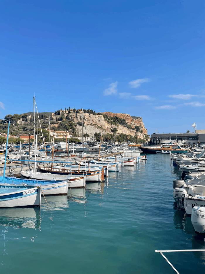 Cette image saisit la beauté enchanteresse du port de Cassis, une perle de la côte méditerranéenne. Les eaux cristallines du port reflètent les bateaux colorés amarrés le long du quai. Les façades des maisons provençales bordant le port ajoutent une touche de charme authentique à ce paysage maritime. Le port de Cassis est le point de départ idéal pour explorer les calanques spectaculaires de la région. Les cafés et les restaurants en plein air offrent aux visiteurs l'occasion de déguster des spécialités locales tout en admirant les vues imprenables sur la mer. Cassis est une destination qui éveille tous les sens, de la vue à la saveur, en passant par l'odeur de la mer salée. Une visite ici est une escapade méditerranéenne par excellence, une aventure où l'on peut se perdre dans la beauté naturelle de la côte provençale.