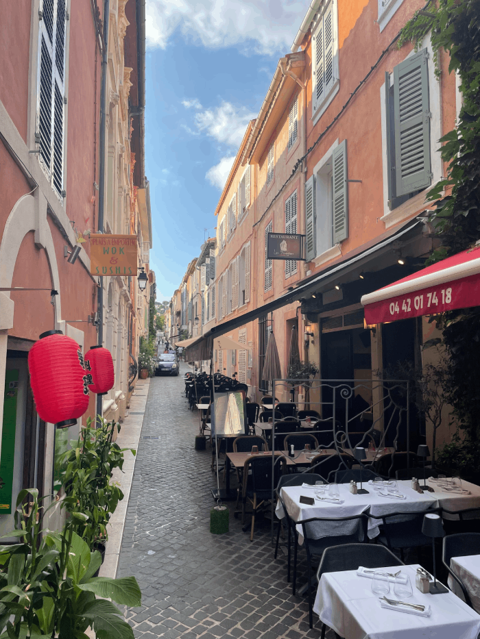 Cette image capture la magie des rues pittoresques de Cassis, un joyau méditerranéen où le charme provençal rencontre la beauté côtière. Les ruelles étroites et pavées, bordées de maisons aux volets colorés, évoquent une atmosphère de village de pêcheurs intemporel. À chaque coin de rue, on découvre des trésors architecturaux et des détails qui racontent l'histoire de la ville. Se promener dans ces rues, c'est se laisser emporter par l'essence de Cassis. Les boutiques artisanales proposent des produits locaux, les cafés en terrasse invitent à la détente et les odeurs de cuisine méditerranéenne flottent dans l'air. L'ombre des platanes offre un refuge bienvenu lors des chaudes journées estivales, créant des espaces où l'on peut se ressourcer et s'immerger dans l'atmosphère méditerranéenne. Cassis est une destination qui charme les visiteurs avec son authenticité et sa beauté côtière. Chaque rue raconte une histoire, chaque coin révèle un morceau de l'âme de la ville. Une visite ici est une aventure au cœur de la Provence, un voyage à travers les sens et l'histoire.